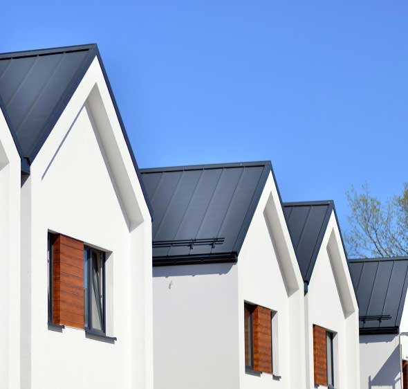 Row of modern residential homes with sleek metal roofing and gabled designs under clear skies, highlighting quality construction and reliable Roofing Fort Pierce, FL services.