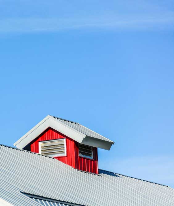 Close-up of a metal roof with red dormer and ventilation detail under clear skies, highlighting durable design and professional Roof Repair Gifford, FL services.
