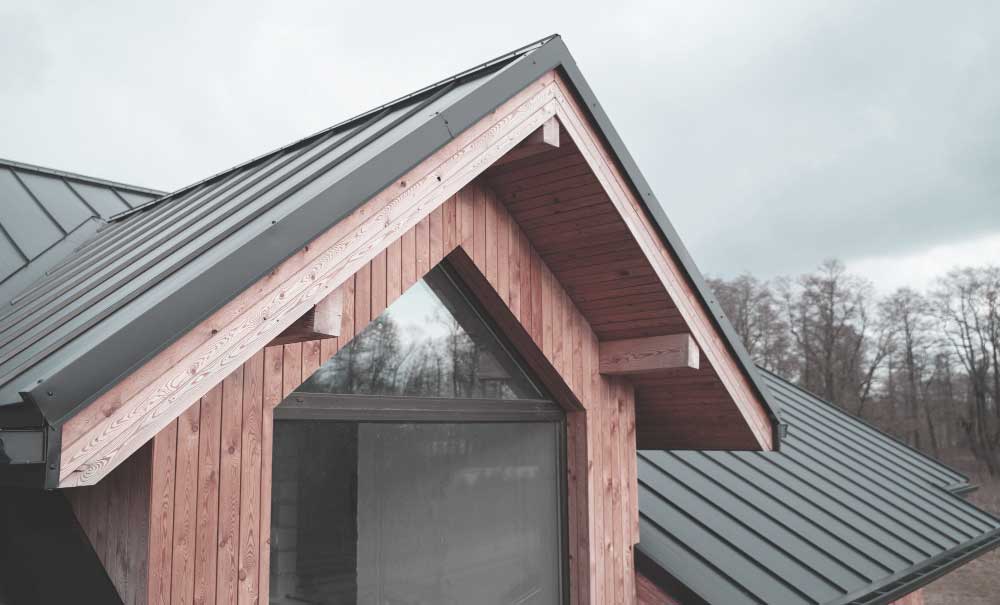 Close-up view of a modern residential home with a standing seam metal roof and wood gable detail, showcasing quality craftsmanship and professional Roofers in Sebastian, FL services.